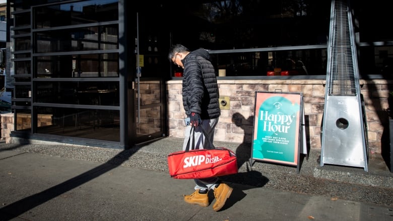 A man walks with a food delivery bag.