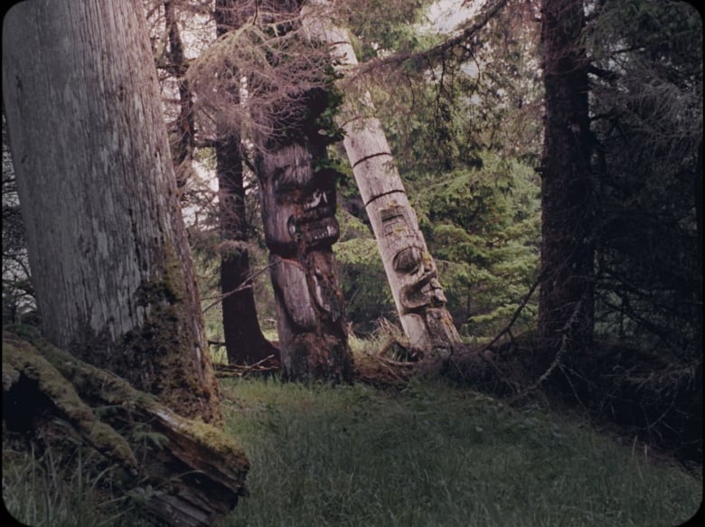 Totem poles are pictured in the woods.