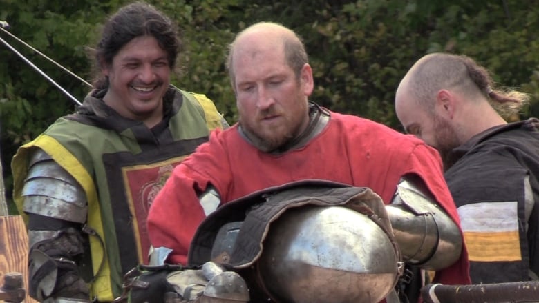 three men in medieval combat armour talk with each other