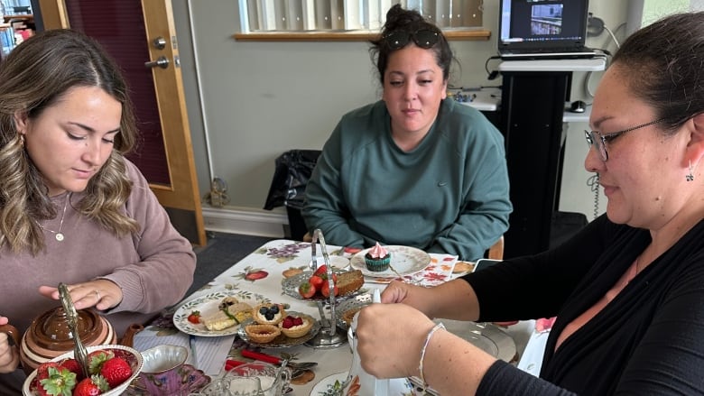 Women sit around a table drinking tea.