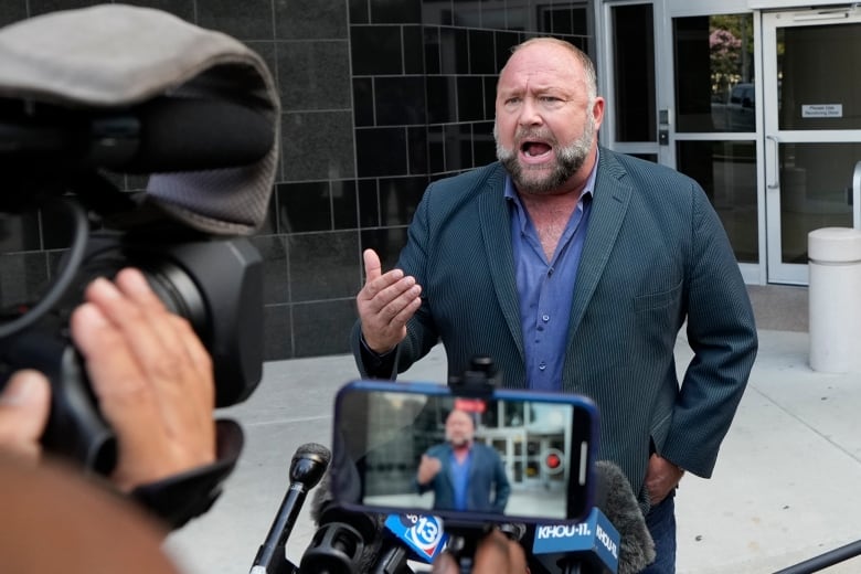 Right-wing conspiracy theorist Alex Jones speaks to the media as he arrives at the federal courthouse for a hearing in front of a bankruptcy judge Friday, June 14, 2024, in Houston. The judge is expected to rule on whether to liquidate Jones' assets to help pay the $1.5 billion he owes for his false claims that the Sandy Hook Elementary School shooting was a hoax. (AP Photo/David J. Phillip)