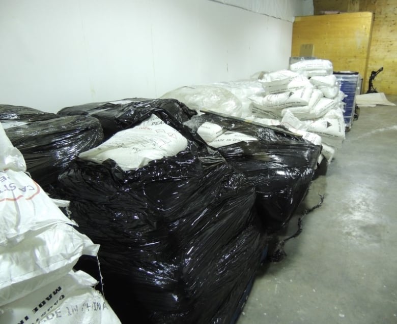 A room filled with white and black bags on a grey floor. 