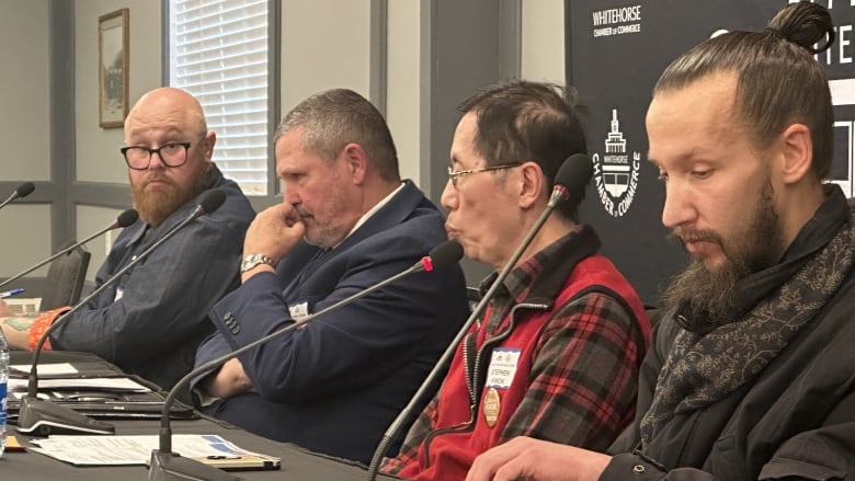 Four men sit at a table during a political debate.