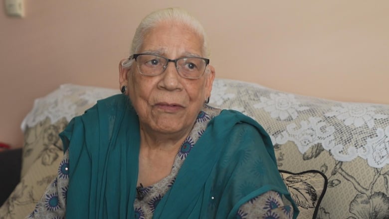 A woman wearing glasses sits on a couch.