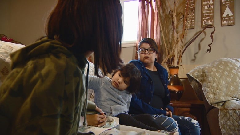 Two girls sit beside their mother on a couch