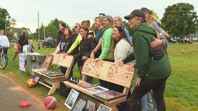 People gathered for a group photo beside a wooden bemch.