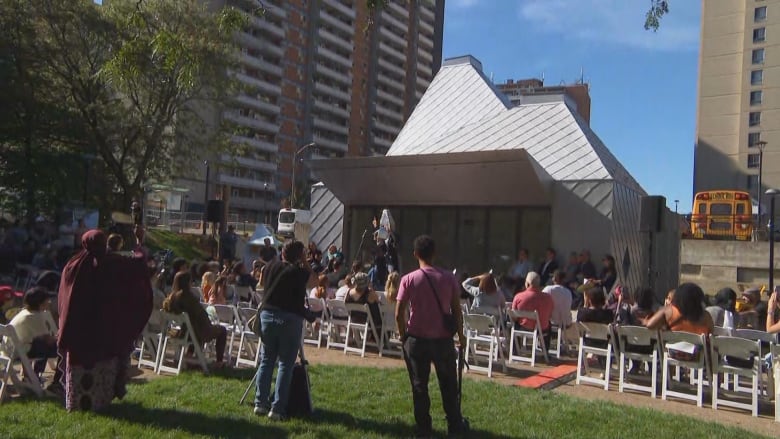 Photo of people in a park listening to a speech