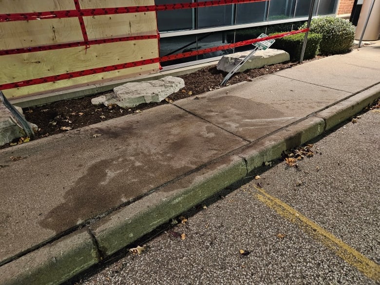 A stain from a liquid is shown on a sidewalk at the back of the CAS building in Windsor where windows were smashed out.