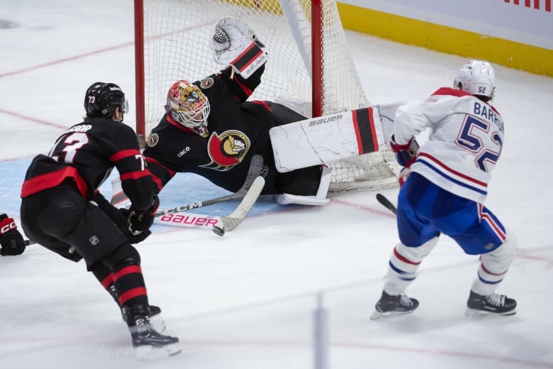 A hockey goaltender sprawls on his side to make a save.