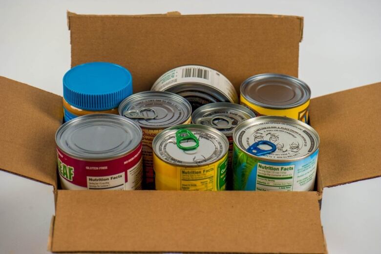 Several canned goods inside a cardboard box