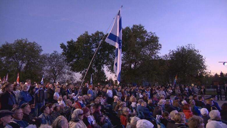 A crowd is seen, with one person holding up a large Israeli flag.