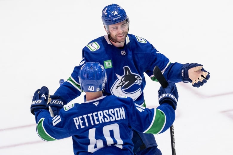 A hockey player smiles as he looks to embrace another one.