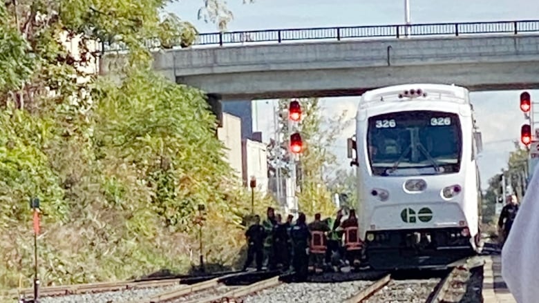 Stopped GO train on tracks with emergency crews off to the side