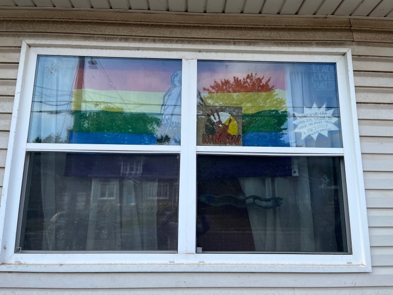 A two-spirit Pride flag hands across the top of a window.