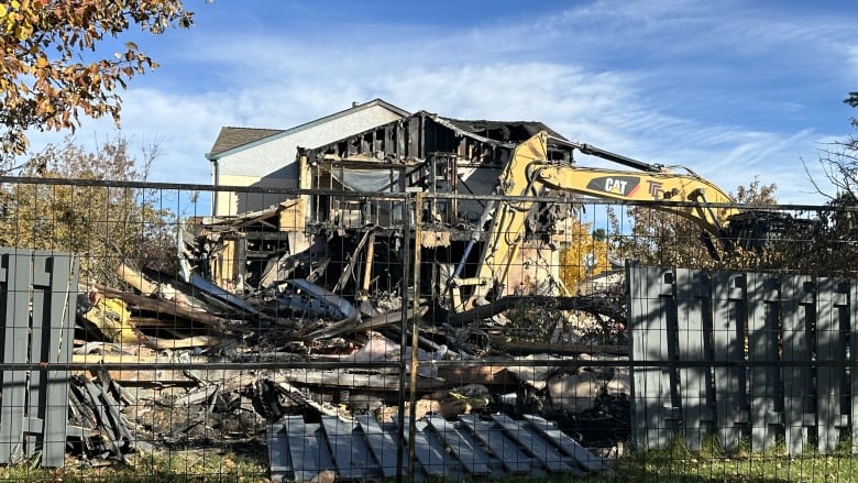 A burned out house behind police fencing.