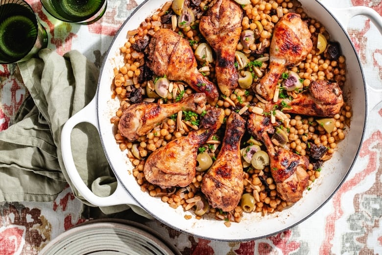 Overhead of a pan of chicken drumsticks on pearl couscous.