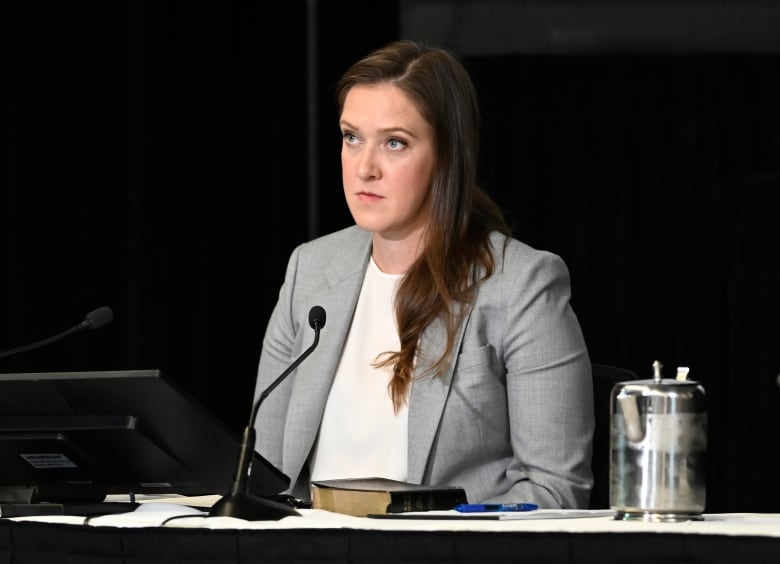 A woman sits before a microphone.