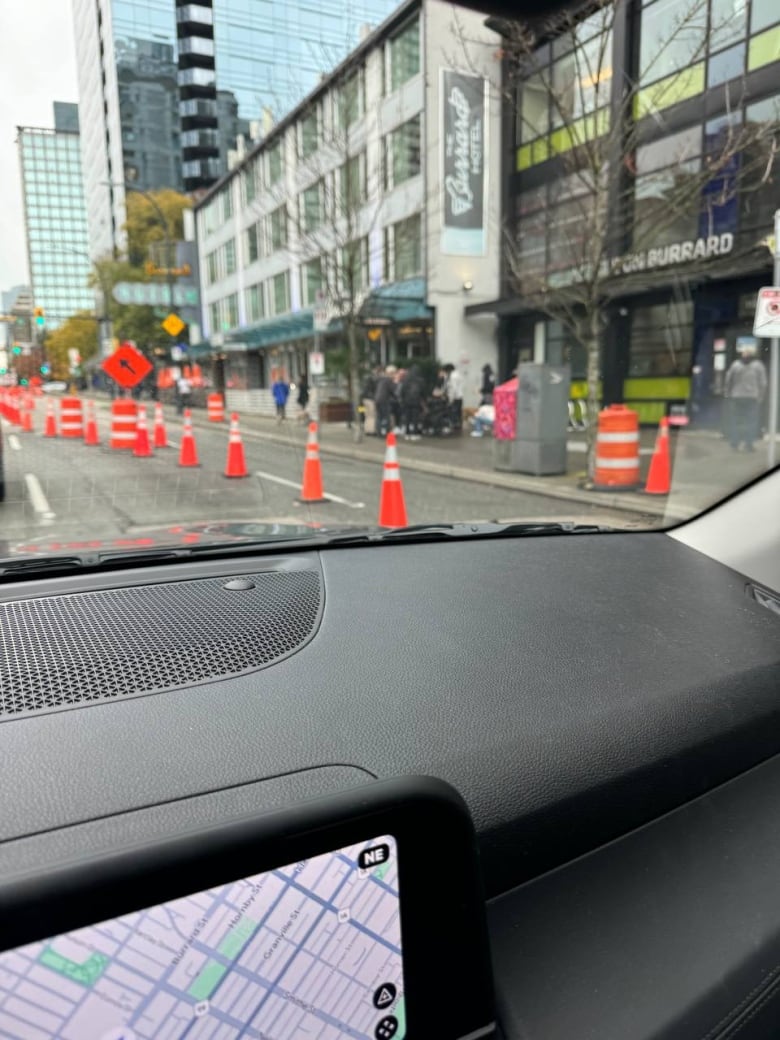 A photo from a car dashboard, with a group of people visible off in the distance gathering around someone.