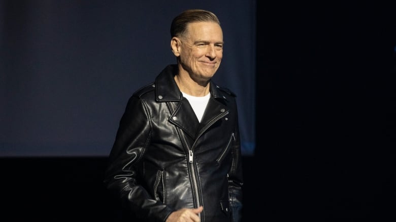 A man in a leather jacket smiles. 