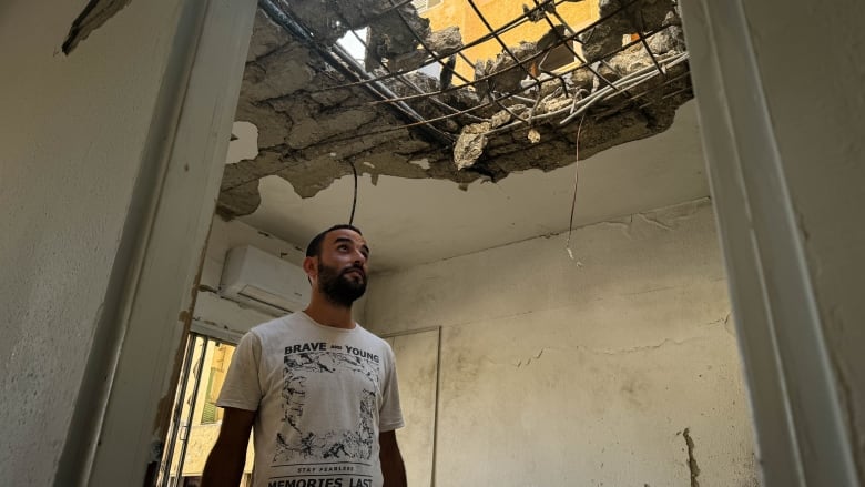 Building maintenance manager David Vaknin looks through the hole that Hezbollah punched in the roof of an apartment in his building on Tuesday.  He had been in the apartment just moments earlier.