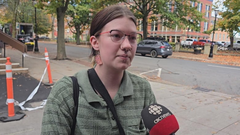 A person wearing a green shirt and dangly earrings