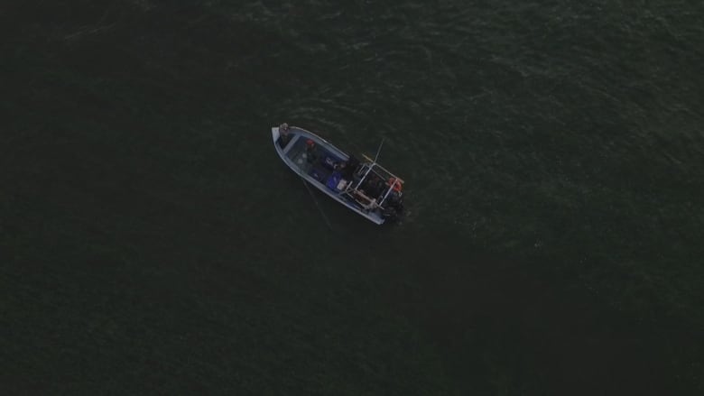 An aerial shot of a commercial fishing boat on a large lake.