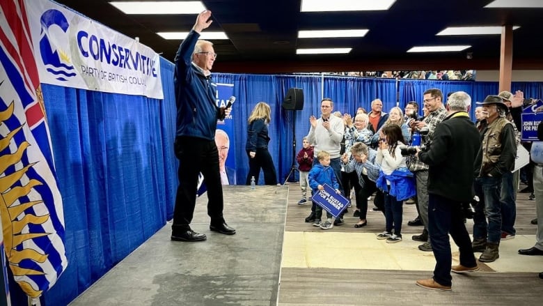 A man on stage while a crowd cheers.