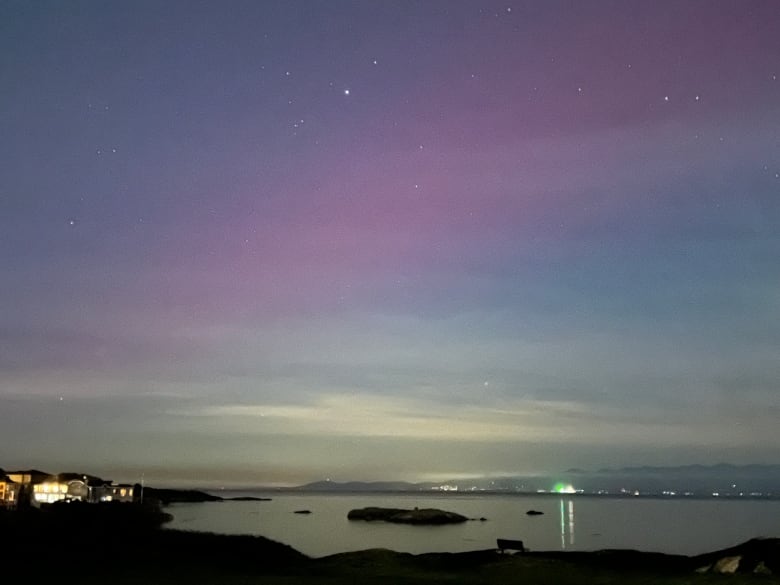 Purple light in the sky above a dark bay.