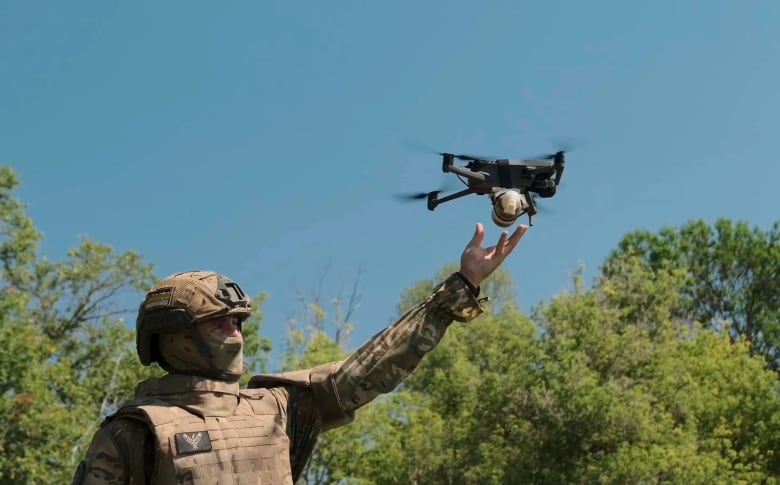 A soldier holds a drone aloft as it takes off. 