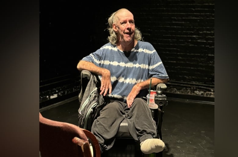 A man in a wheelchair sits in a theatre.