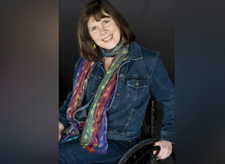 A smiling woman sits in a wheelchair.