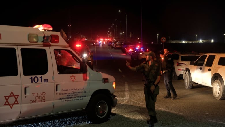 Emergency personnel direct an ambulance amid traffic