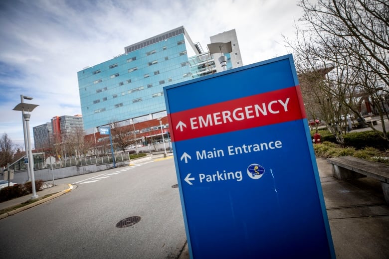 A sign pointing to a hospital's emergency department, main entrance and parking.