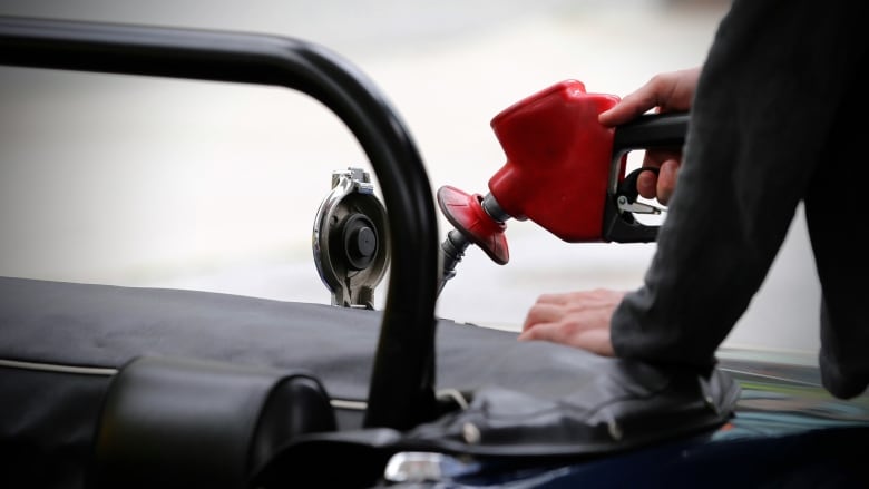 A close-up of a person filling their gas tank at a gas station.