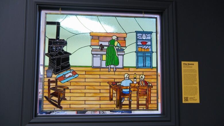 Stained Glass artwork depicting women washing dishes in old home, with children sitting at table. 