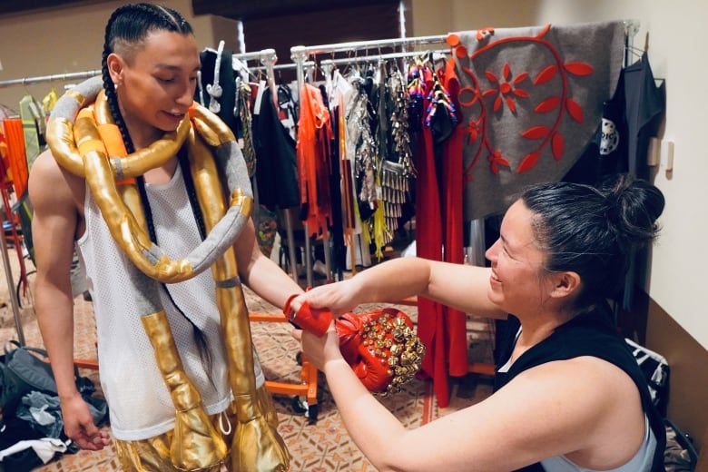 Women adjusts costume on model.