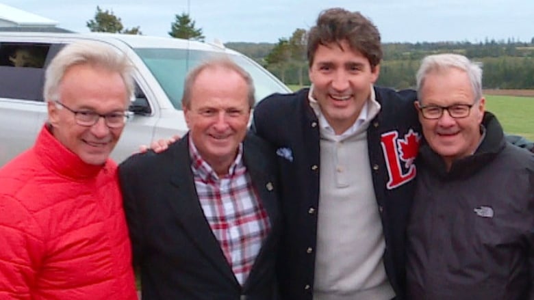 Four men posing with arms around each other.