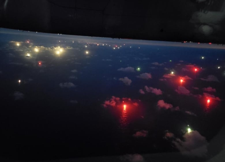 Red lights glow over a cloud-speckled ocean.