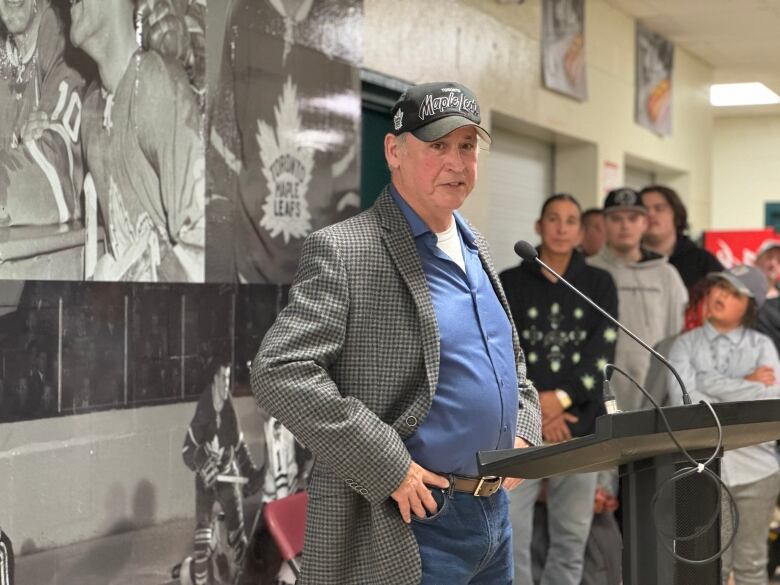 A man in a Maple Leafs hat stands at a podium