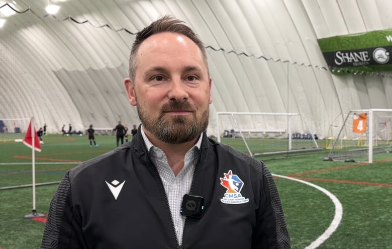 Executive Director of Calgary Minor Soccer Association, Carlo Bruneau, stands on an indoor soccer pitch.