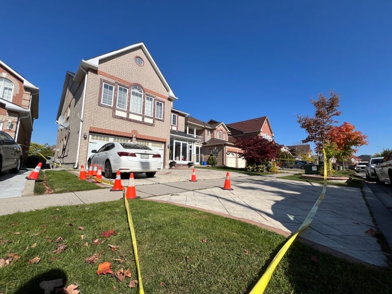 Photo of a house with orange pylons and police tape. 