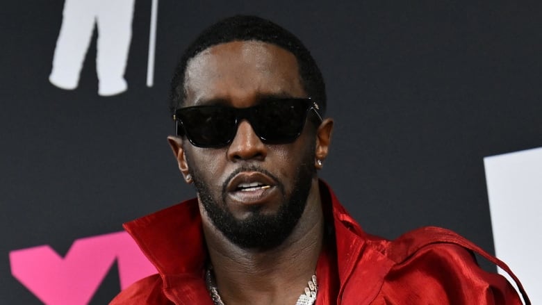 A photograph of Sean (Diddy) Combs in a red jacket and sunglasses. 