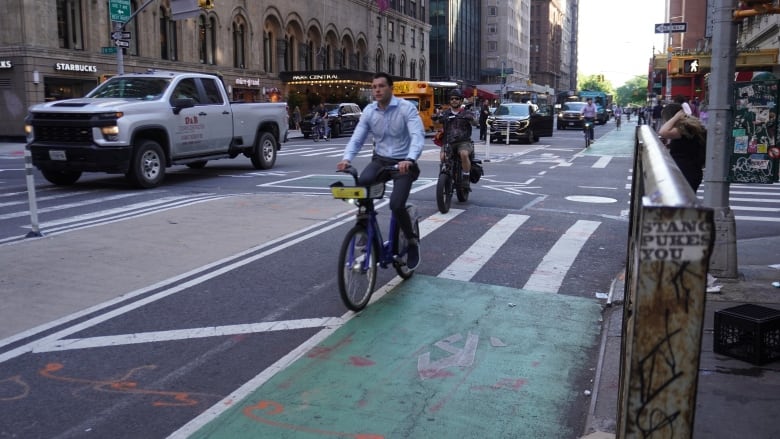 A cityscape that shows traffic and a man on a bicycle.