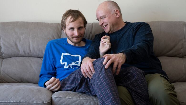 Andrew Kavchak and his son Steven pose for a photo on the sofa in their home in Ottawa, Friday, March 3, 2023. Kavchak, 60, a former federal public servant, retired to provide care for his son Steven, 22, who lives with autism spectrum disorder.