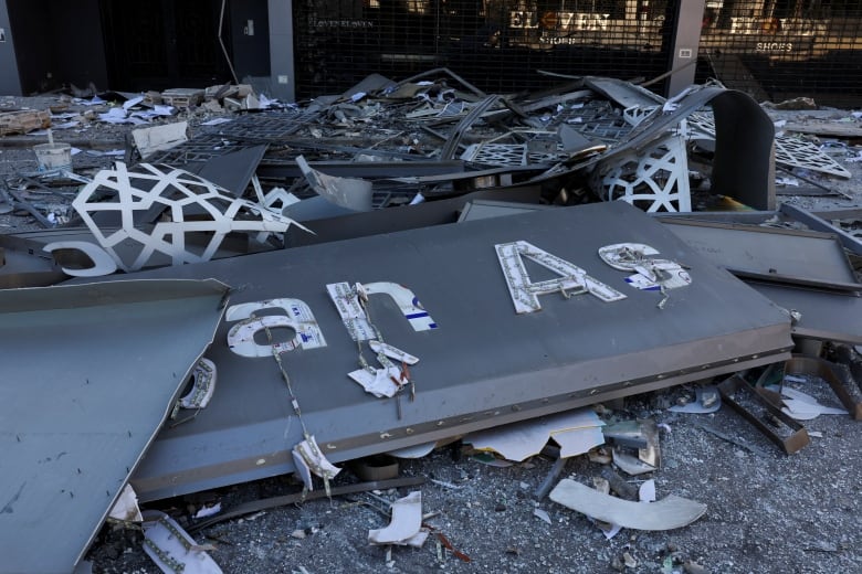 A broken sign lies among debris on the ground.