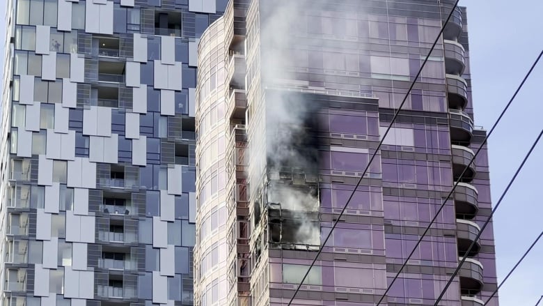 Smoke and soot emanate from at least four floors of an apartment building.