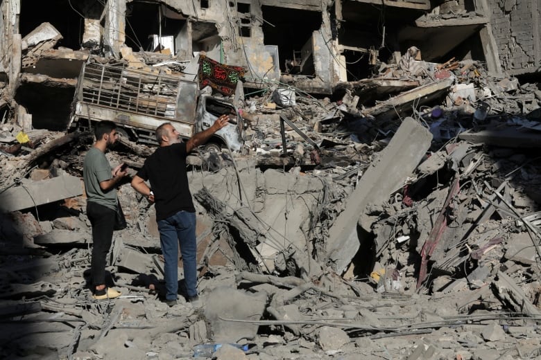 People stand on the rubble at the site of the Israeli airstrike that killed Lebanon's Hezbollah leader Sayyed Hassan Nasrallah on Friday, in Beirut's southern suburbs, Lebanon, September 29, 2024. 