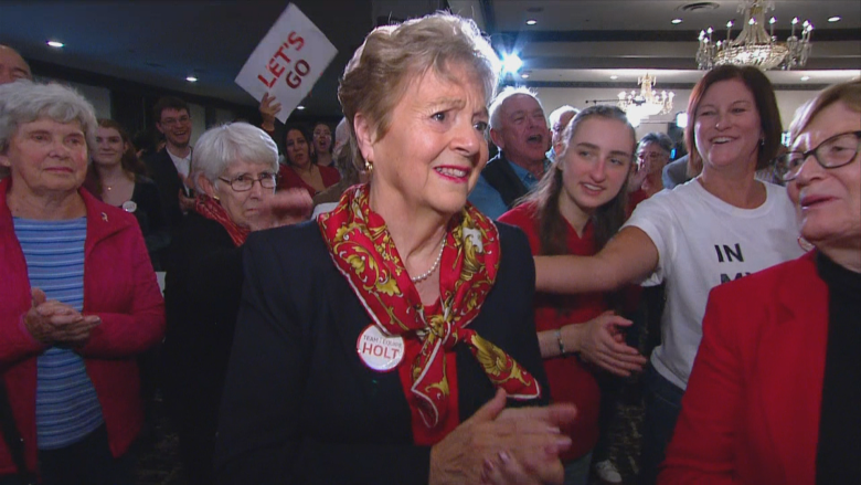 A woman smiling and tearing up in a crowd.