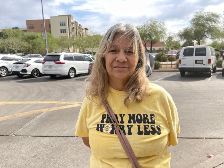 A woman in a yellow t-shirt in pictured in a parking lot.