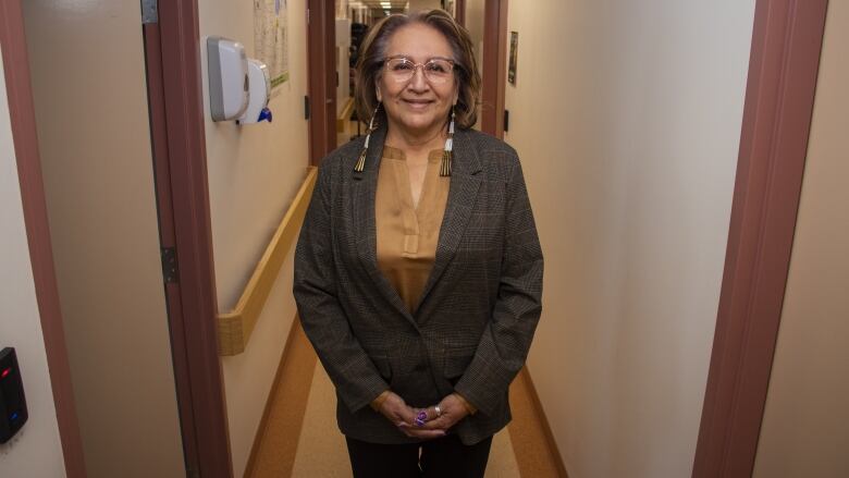 A woman stands in a hallway.